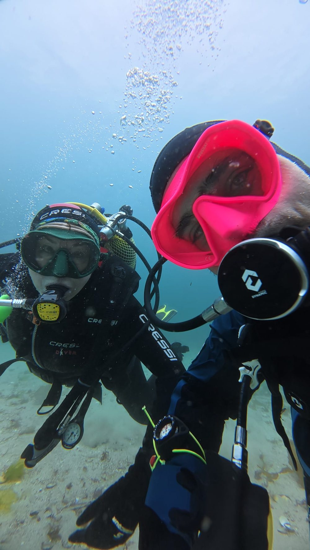 Dos buceadores compartiendo un momento bajo el agua
